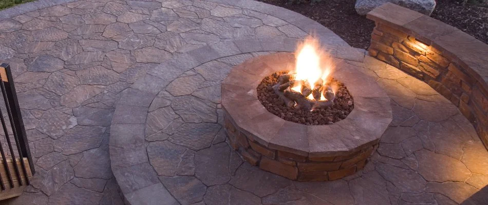 Round fire pit on a patio in Lititz, PA, with a seating wall.