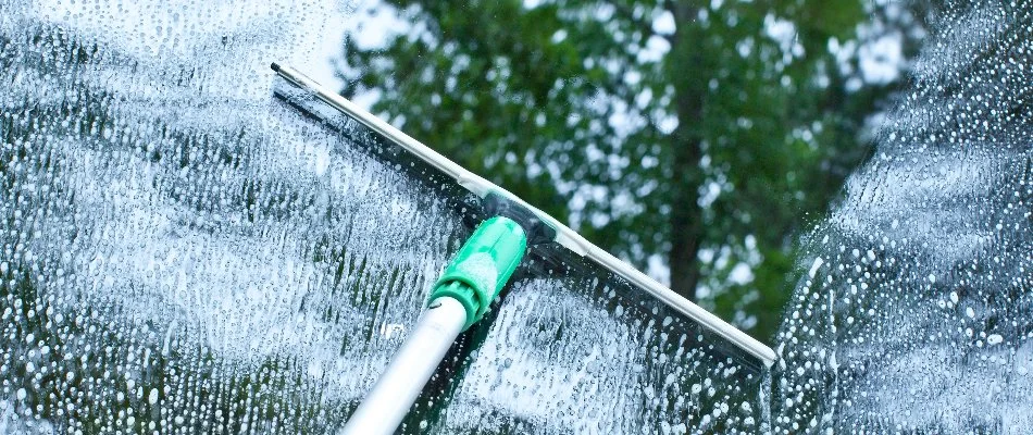 A squeegee cleaning a window with soap in Lititz, PA.