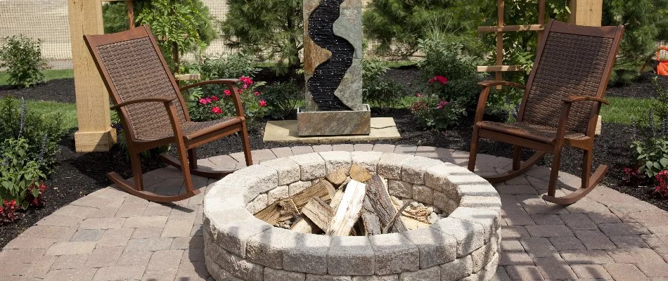 Wood-burning fire pit next to two rocking chairs.